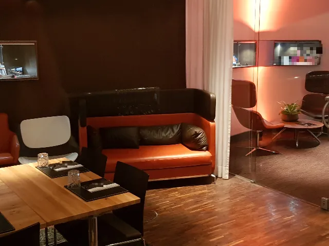 Empfangs- und Besprechungsbereich mit orangefarbenem Sofa, Holztisch und Glaswand